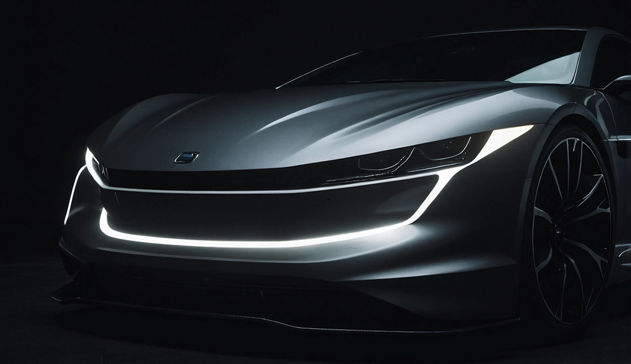Close-up of a sleek silver electric sports car front with illuminated LED headlights and a glowing light strip outlining the grille.