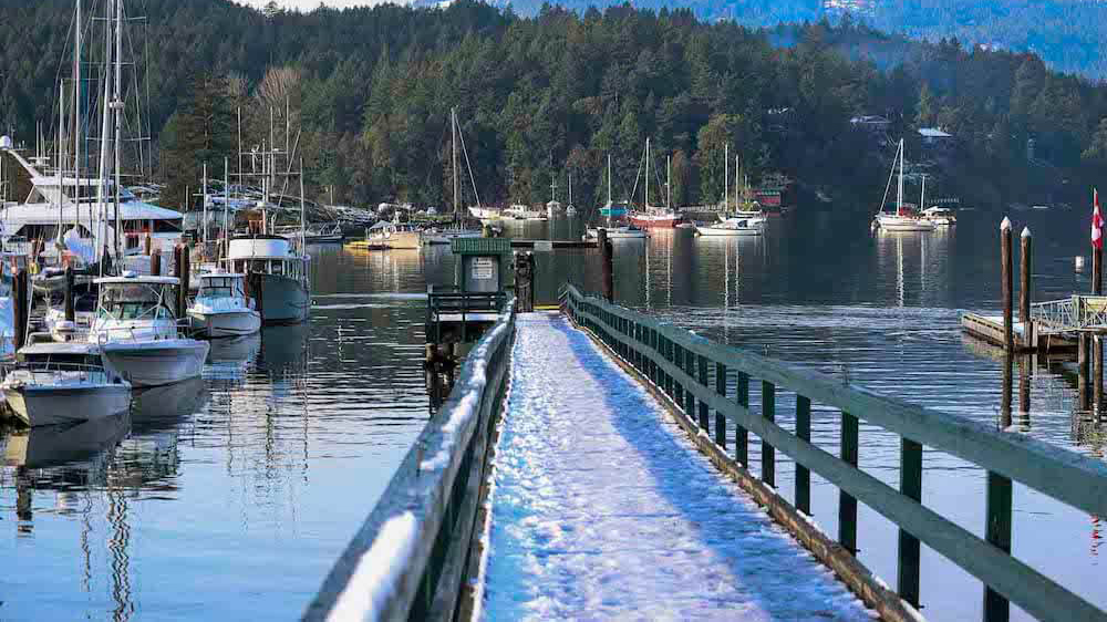 Boats in the water on a winter day with snow on the ground in Brentwood Bay BC