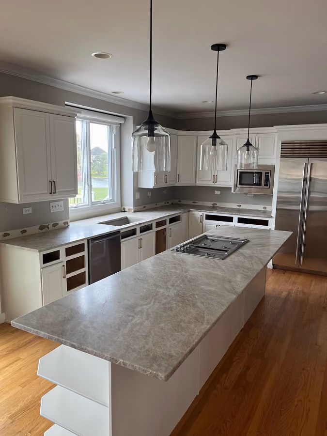 Modern kitchen featuring Taj Mahal quartzite countertops with warm beige veining, waterfall island design, white cabinetry, and pendant lighting. Kitchen island in Barrington, IL, with a Taj Mahal Quartzite countertop, highlighting the natural stone’s subtle beige tones and elegant veining.