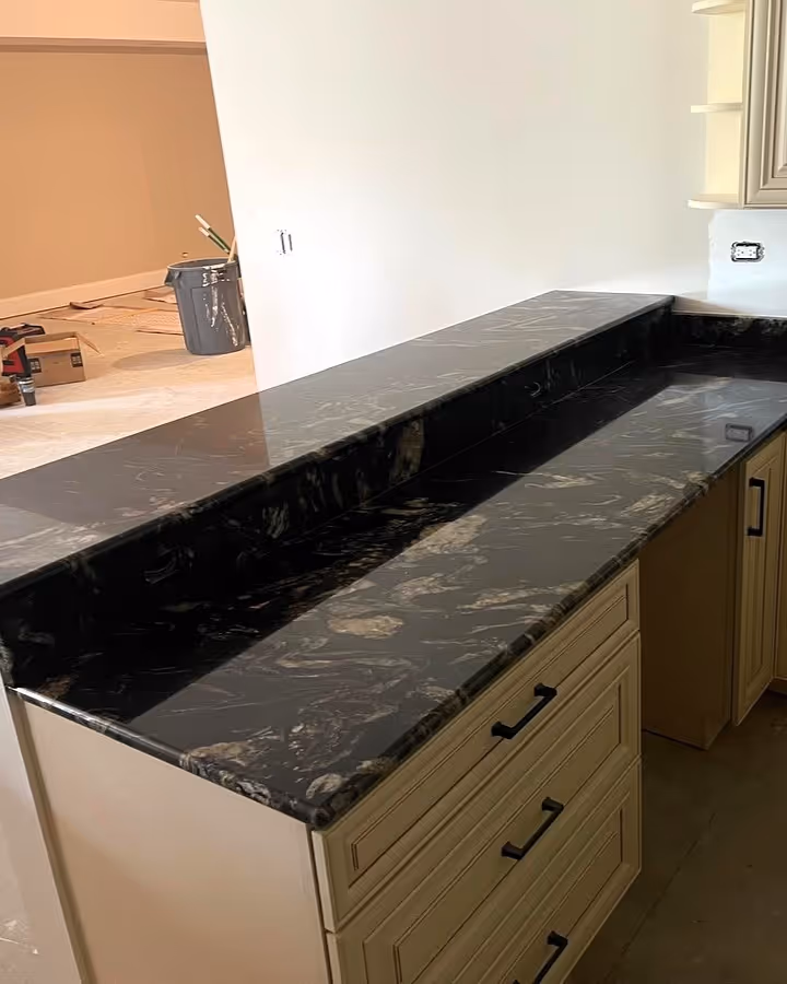 Bar-height countertop installation using titanium granite stone with elegant gold and black veining.