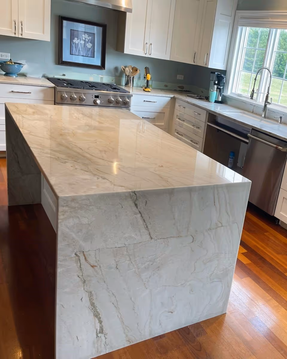 Elegant Taj Mahal Quartzite island with waterfall edge, adding warmth and luxury to a bright kitchen.