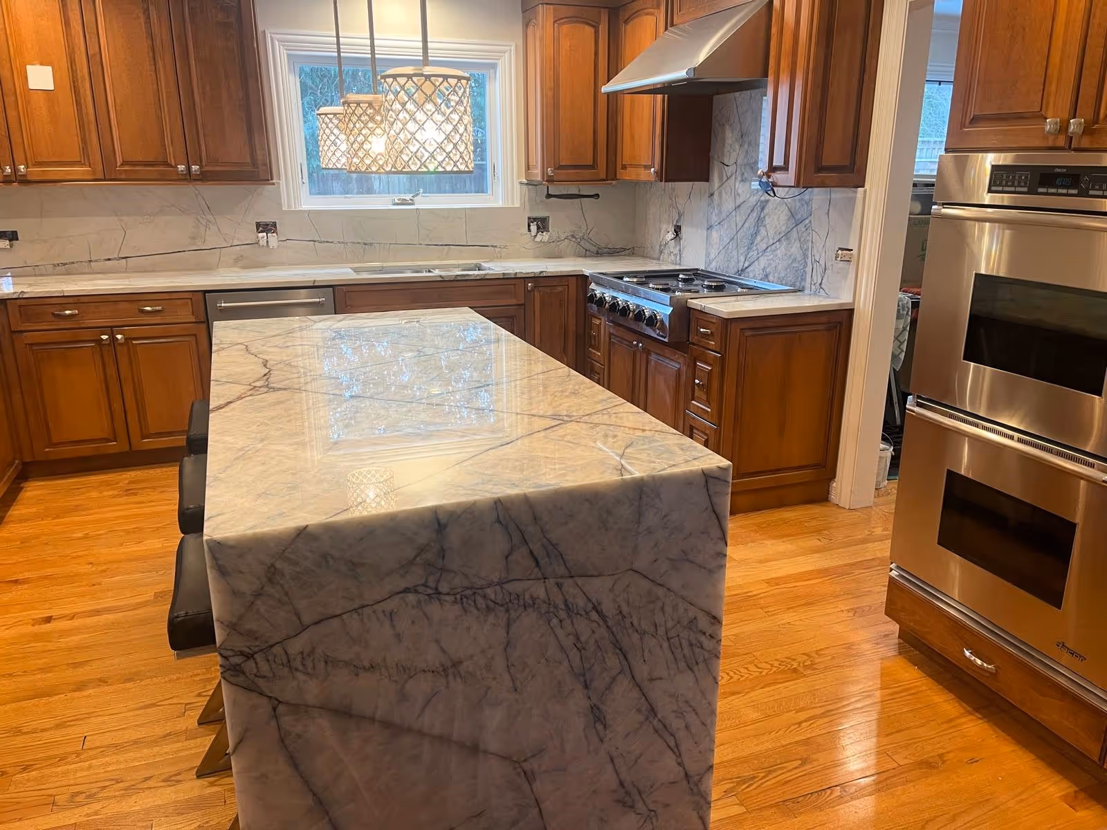 Luxury kitchen featuring a quartz island with built-in cooktop, stainless steel appliances, and custom cabinetry.