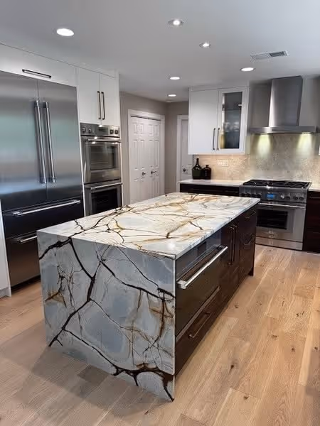 Large kitchen island in Oak Brook with Desert Lake Quartzite waterfall edge, contrasted by white cabinetry and stainless steel appliances.