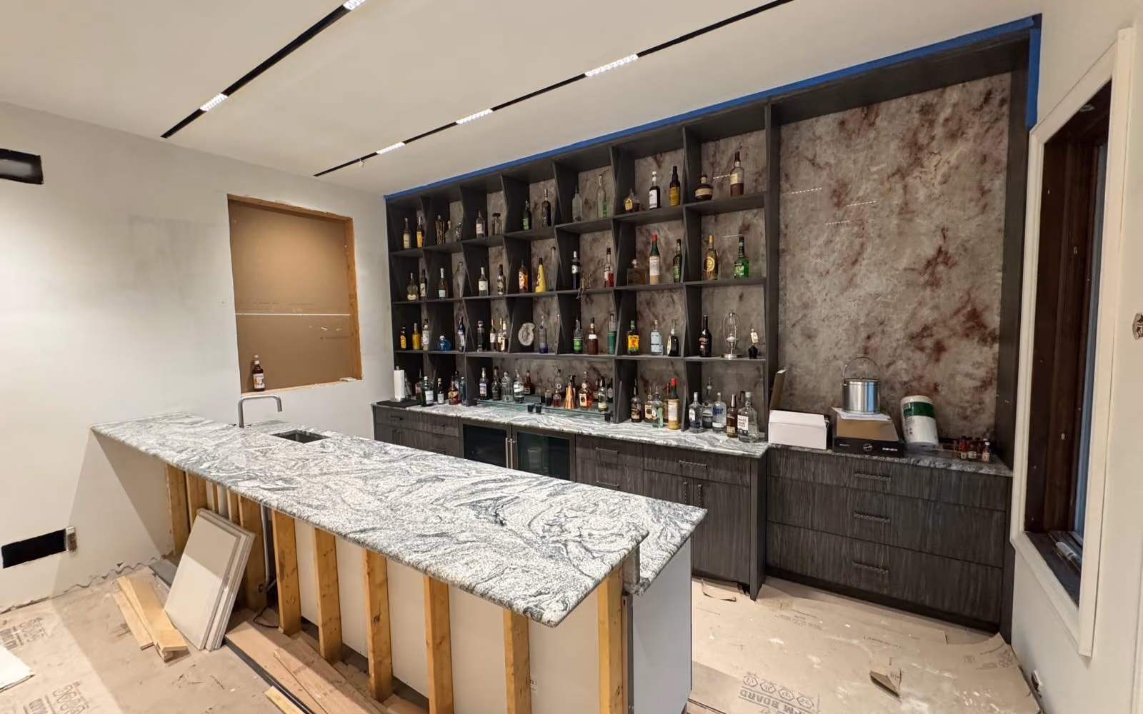 Custom natural stone bar countertop and backsplash installation in the Chicago area Custom bar and kitchen installation with natural stone countertops and full-height stone backsplash