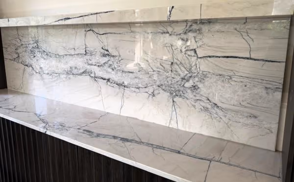Full-height natural stone backsplash with matching polished countertop and dramatic veining