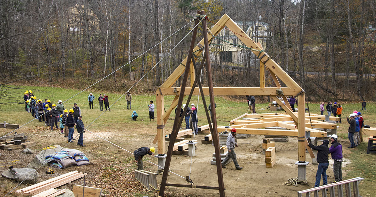 students and volunteers raise the frame of the outdoor pavilion