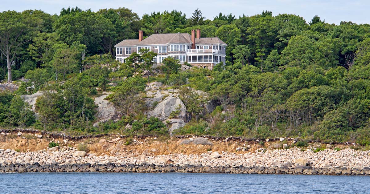A glazed tower extends toward the granite edge, creating a dramatic interior volume and defining one side of the stone terrace.