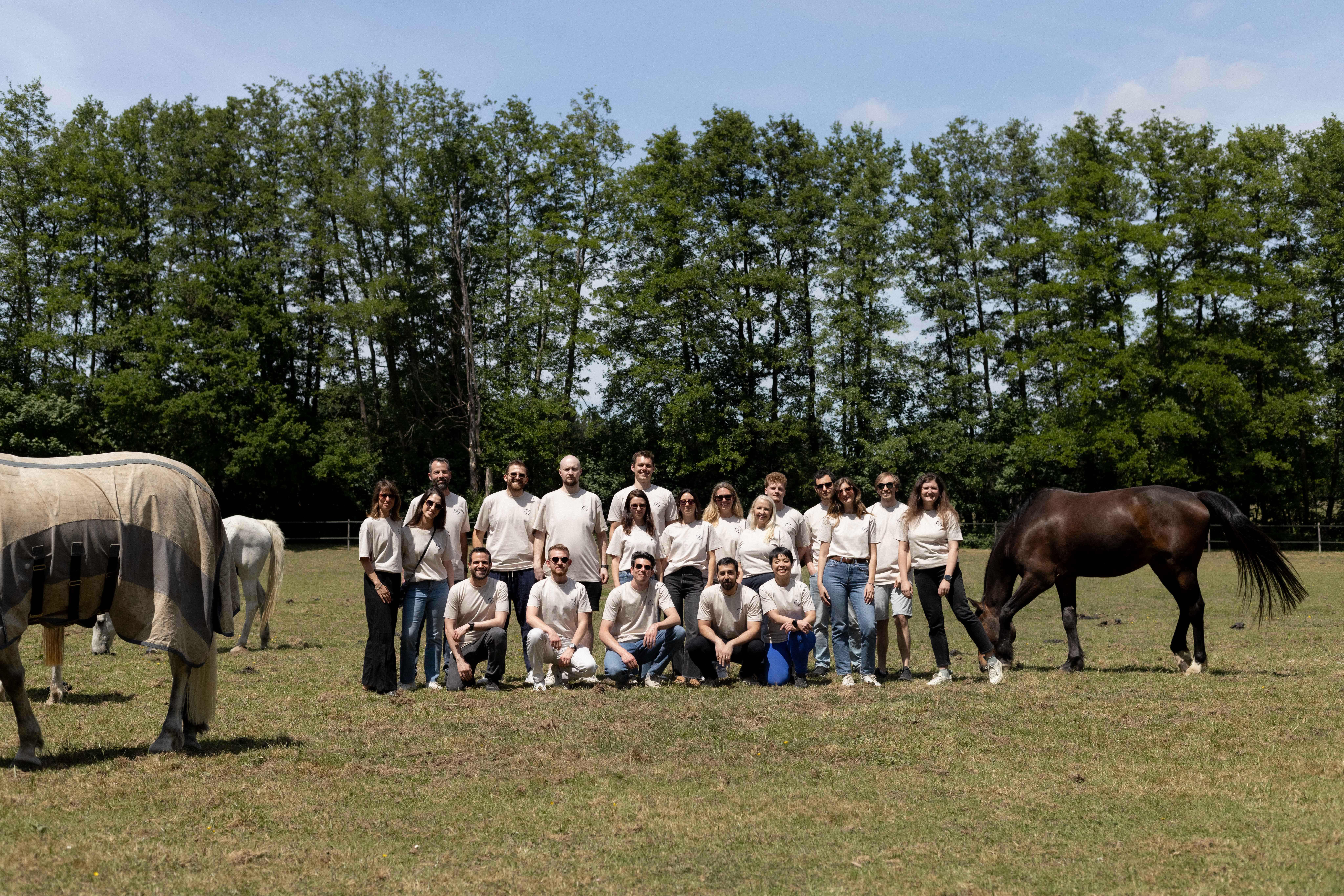 The Nagish team in France standing on the grass next to horses