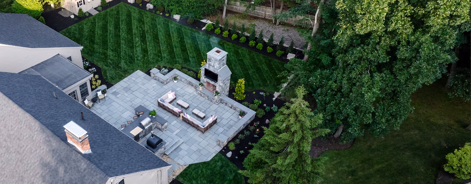 Overhead view of well kept outdoor living area with patio, landscaping, and outdoor fireplace.