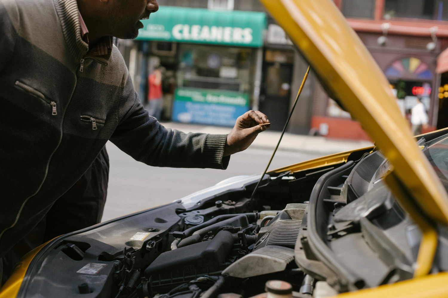 A man is inspecting the oil level of a car.