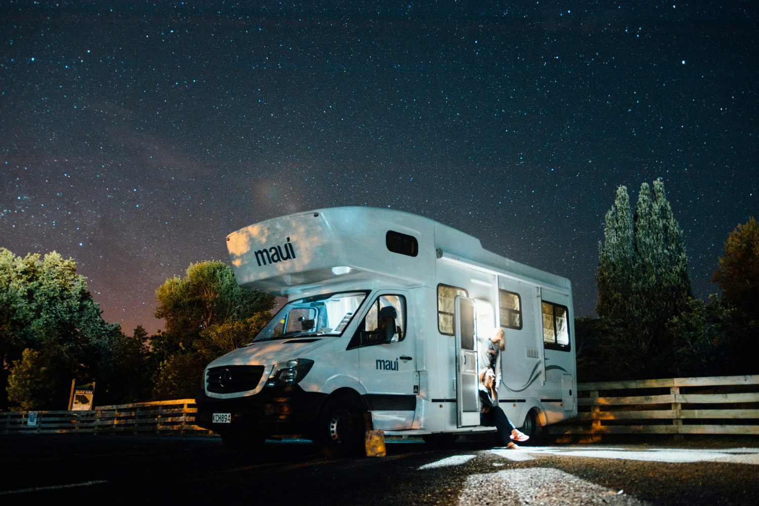 A person standing in front of a camper van at night.