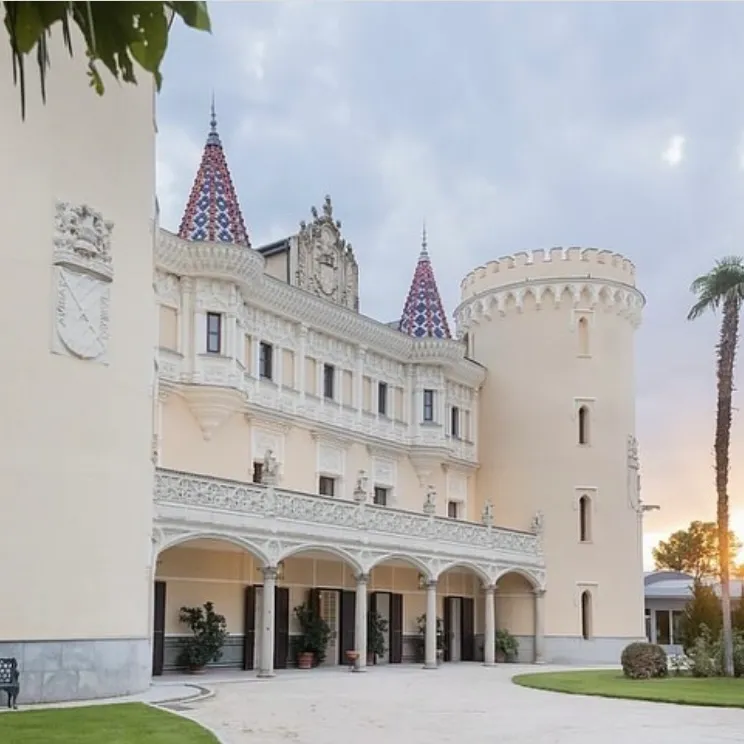 Castillo de Viñuelas blanco elegante con torres puntiagudas de mosaico y jardines verdes
