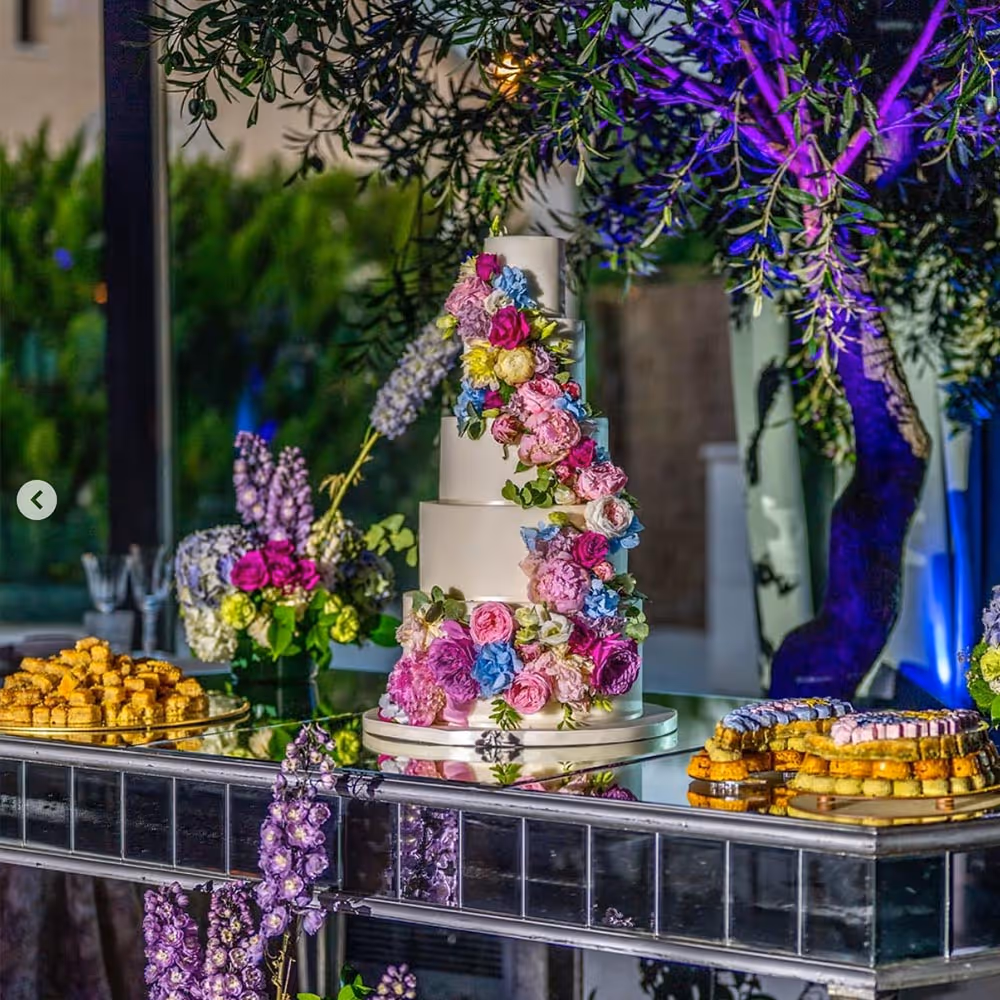 Palmera frente a un edificio histórico con detalles ornamentales y una torre circular bajo un cielo azul.