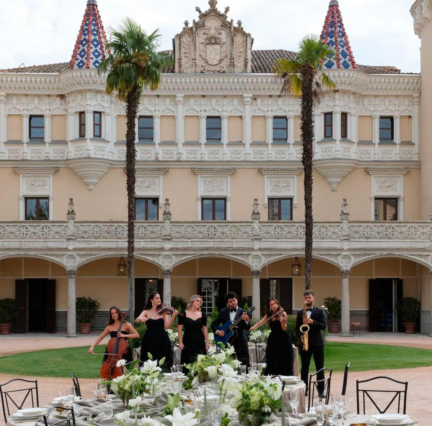 Grupo de músicos tocando instrumentos clásicos y guitarra en un jardín frente a la fachada de Castillo de Viñuelas.