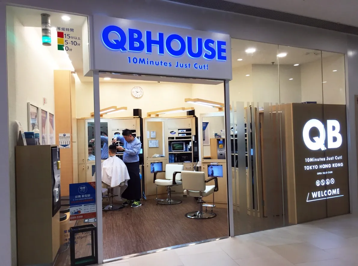 Мінімалістичний салон QB House у Токіо: блакитна вивіска "10 Minutes Just Cut", крісла для швидких стрижок, годинники та автомати — креативний концепт доступних 10-хвилинних зачісок для бізнесменів.