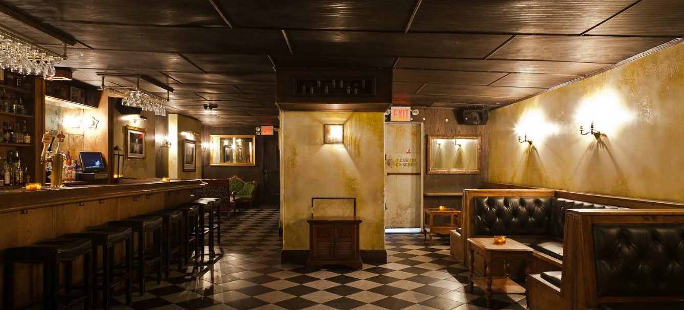 Спікізі-барбершоп The Blind Barber у Нью-Йорку: дерев'яний бар з келихами, шкіряні бусики, шахова підлога та приглушене освітлення — джазова атмосфера, де після стрижки сервірують коктейлі.