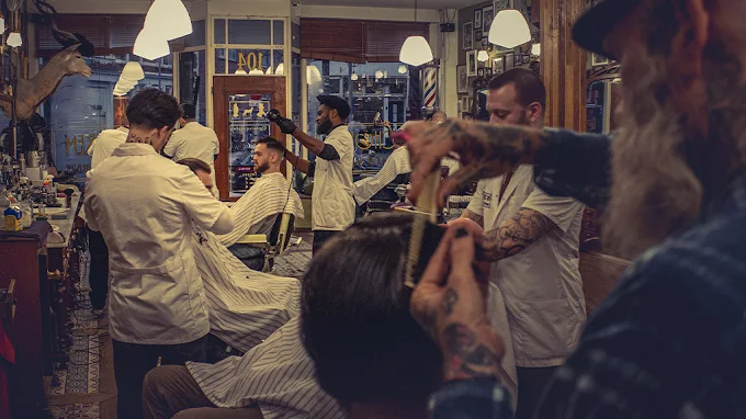 Ретро-барбершоп Schorem у Роттердамі: майстри в білих халатах стригуть клієнтів у класичних кріслах під теплим освітленням ламп, з елементами рок-н-ролу — креативний концепт для фанатів тату та vintage-стилю.