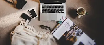 A laptop computer and mobile phones on a carpeted floor