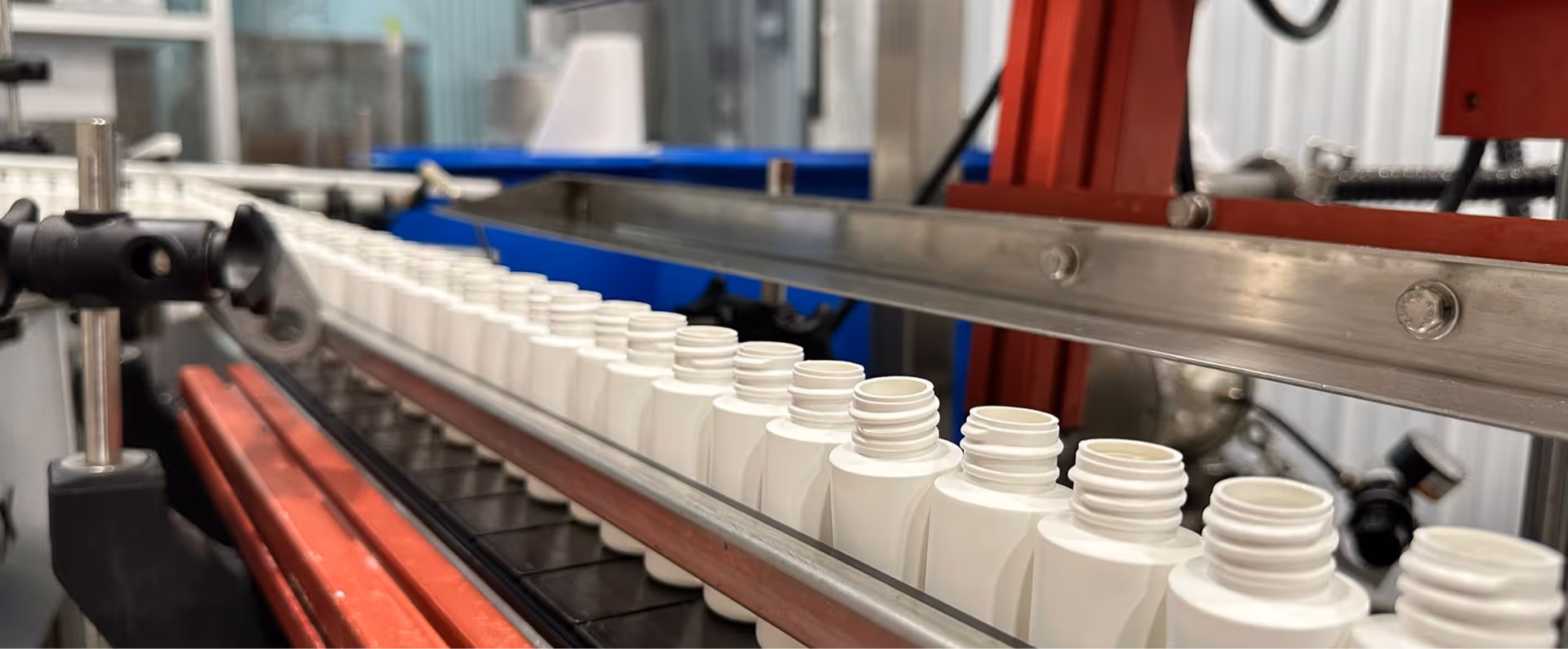 Automated supplement packaging line preparing plastic bottles for filling and sealing in nutraceutical production facility | Steuart Nutrition