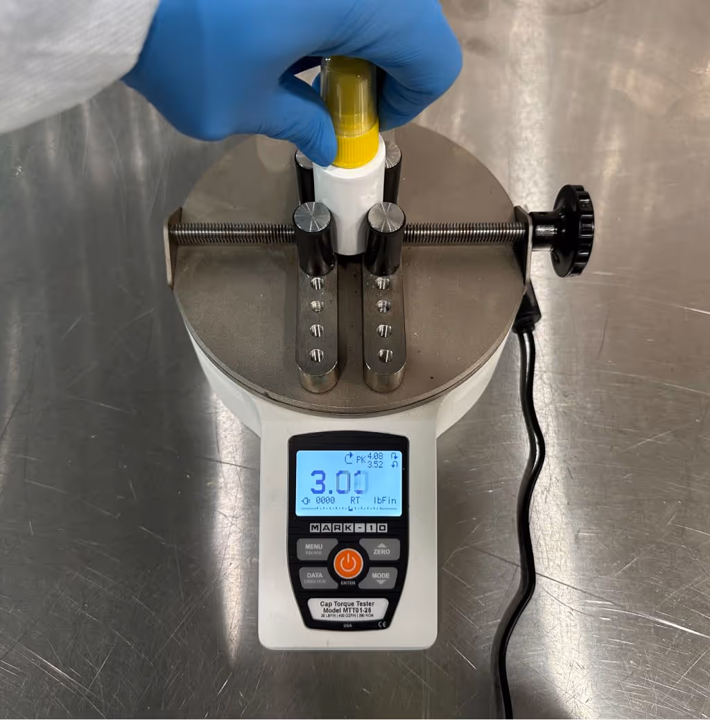 Quality control technician testing bottle cap torque with digital torque meter to ensure packaging integrity in supplement manufacturing | Steuart Nutrition