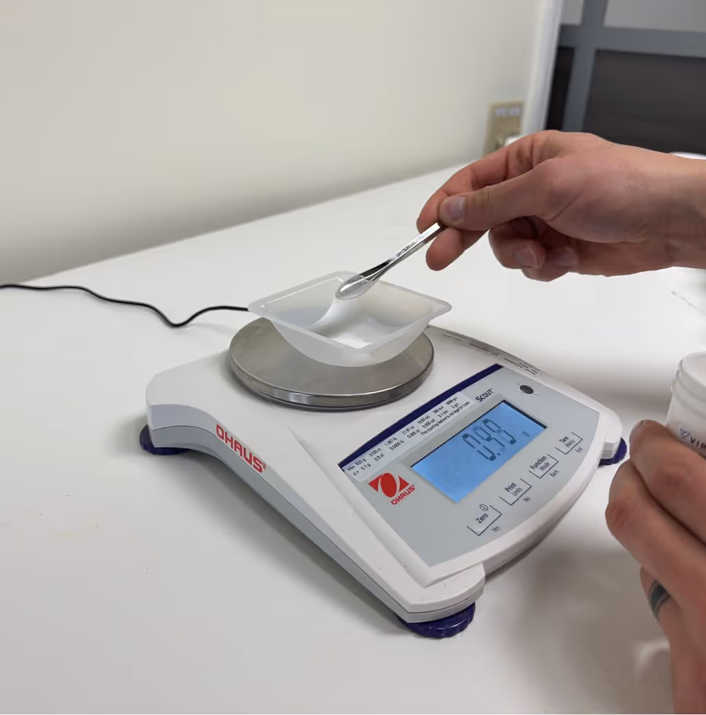 Quality control technician using calibrated digital balance to verify powdered supplement weight and consistency during product testing | Steuart Nutrition”