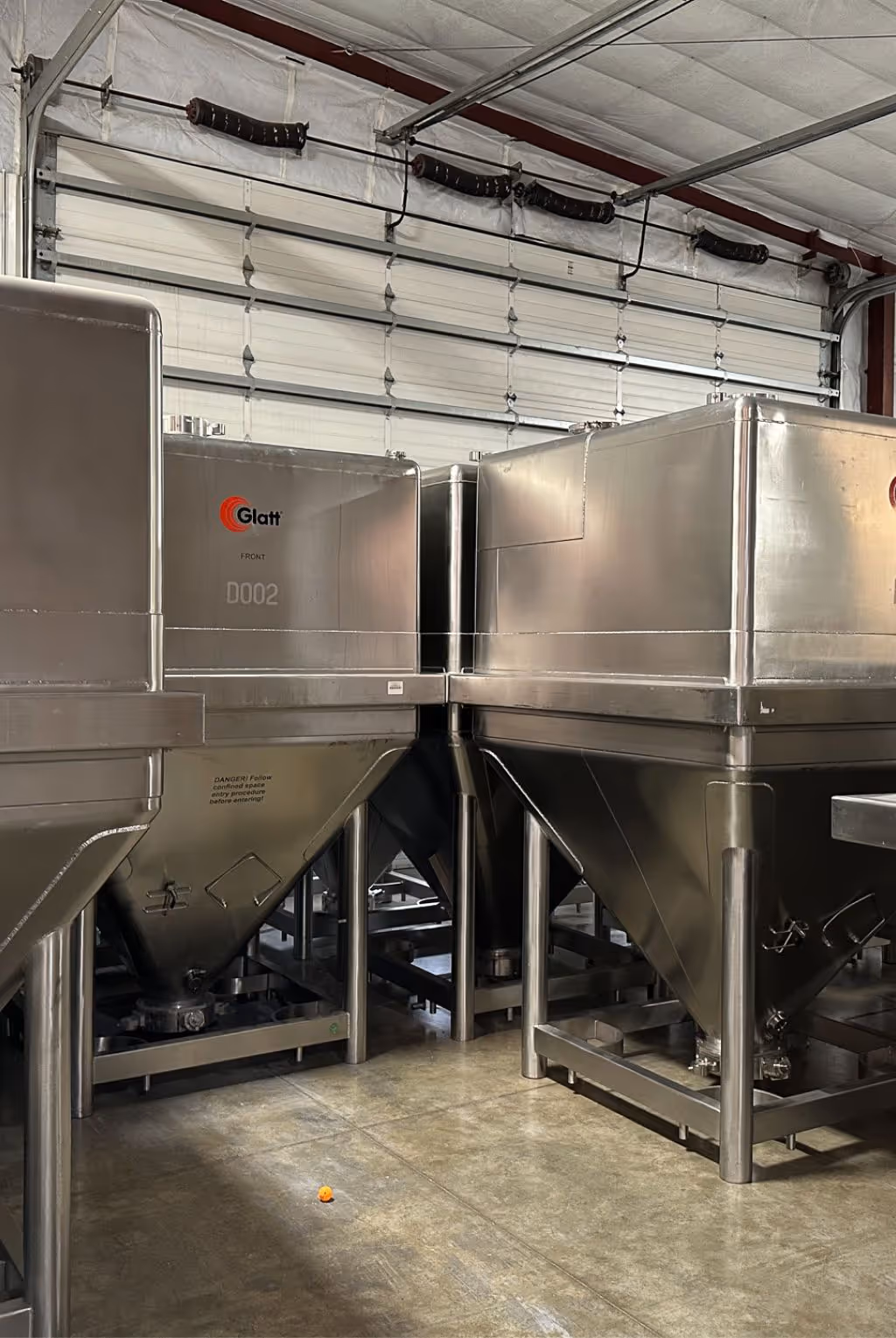 Industrial stainless steel blending hoppers for uniform mixing and storage of powdered supplement ingredients prior to packaging | Steuart Nutrition