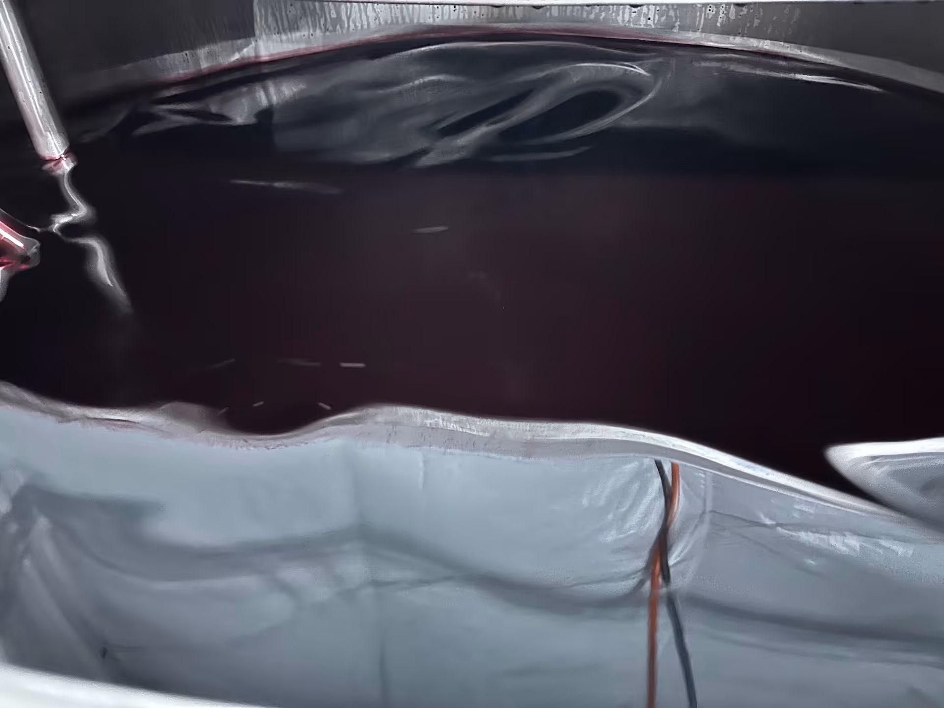 Deep-colored liquid supplement mixture in stainless steel blending tank during formulation and preparation for bottling in manufacturing process | Steuart Nutrition