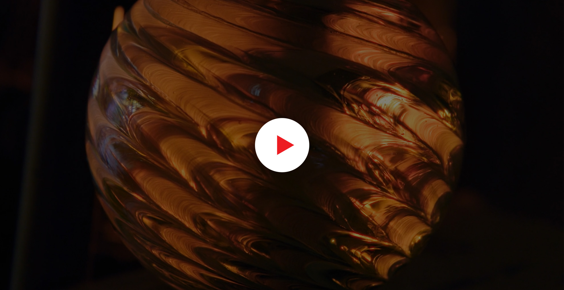 Close-up of a glowing, textured glass object with warm amber tones in dim lighting.