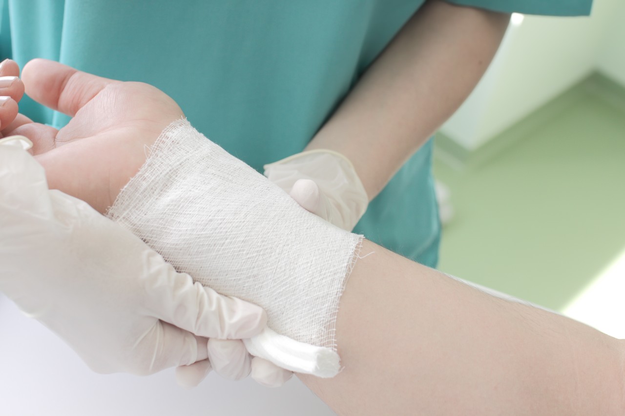 dermatology nurse covering a patient wound with bandage