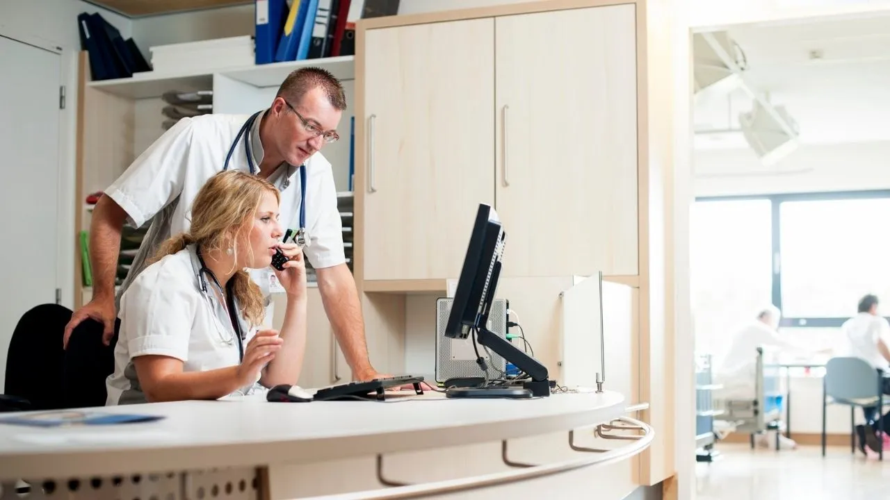 A hospital nurse manager and doctor reviewing a computer