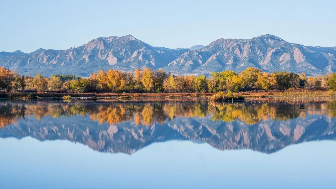 mountains positioned in the backdrop mirroring off the water in the front view