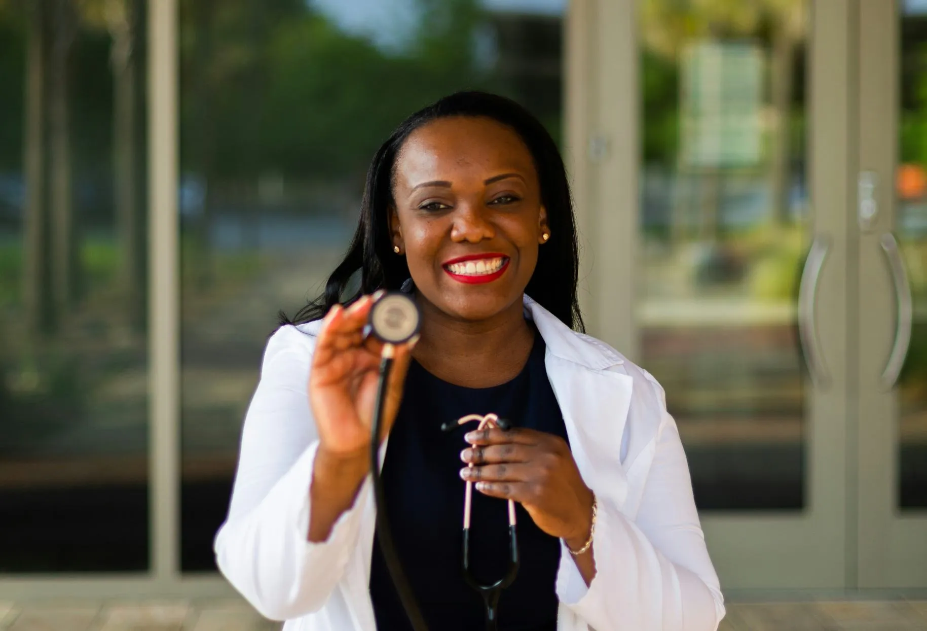 A nurse standing in front of a facility with a stethoscope