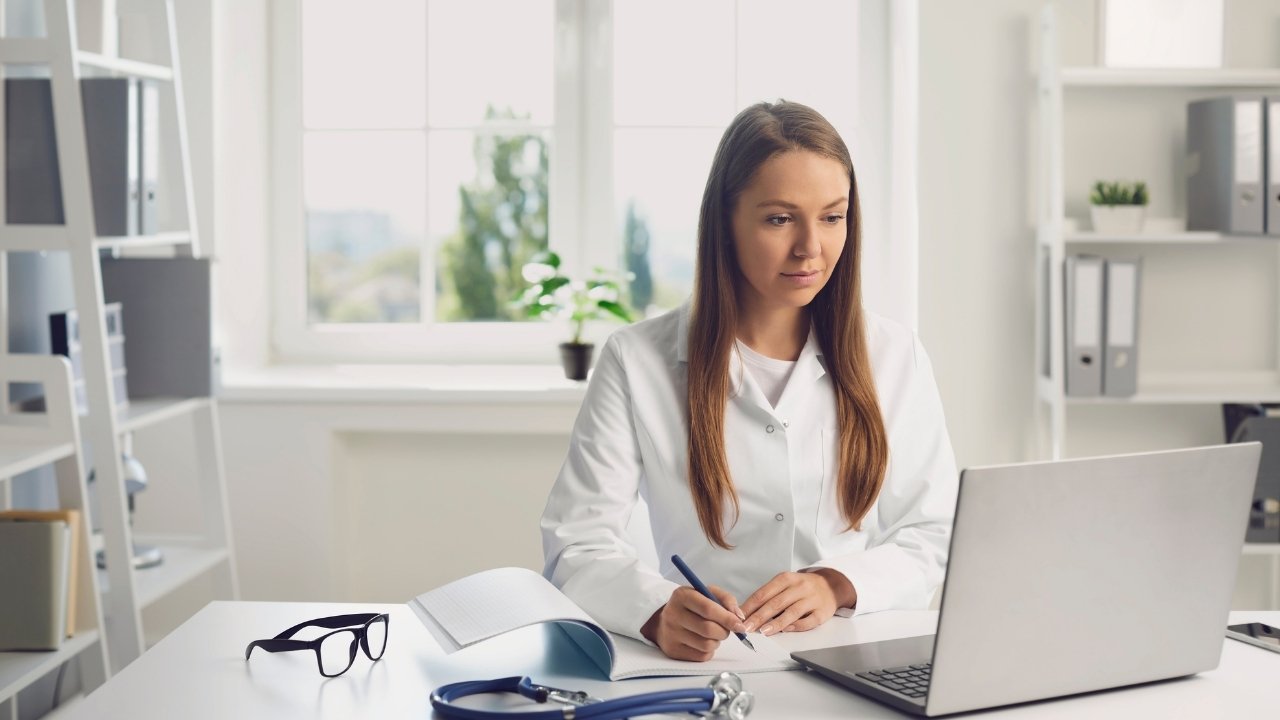 A woman looking at a computer and holding a pen