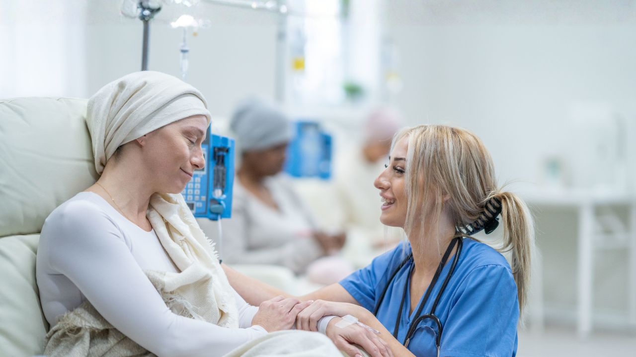 a nurse holding the hand of a cancer patient