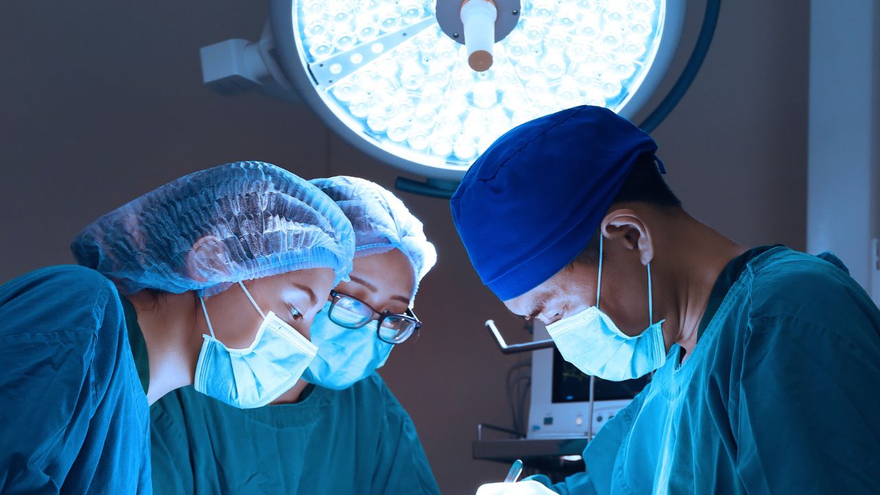 surgeons performing a surgery under bright operating room lights
