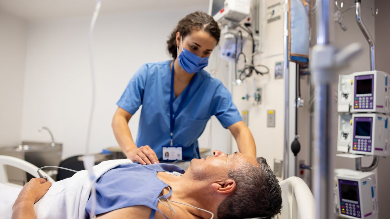 a nurse caring for a male patient lying in a hospital bed