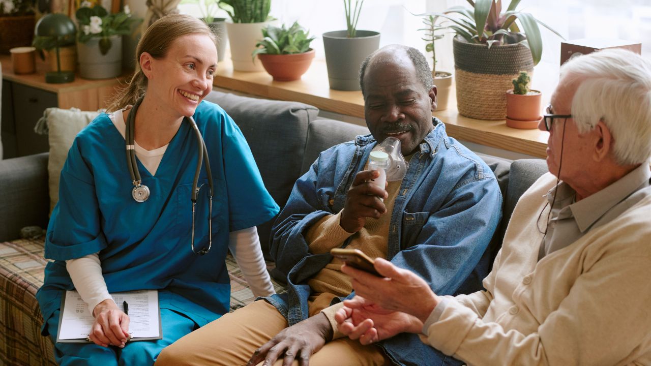 A female nurse visiting two elderly male patients