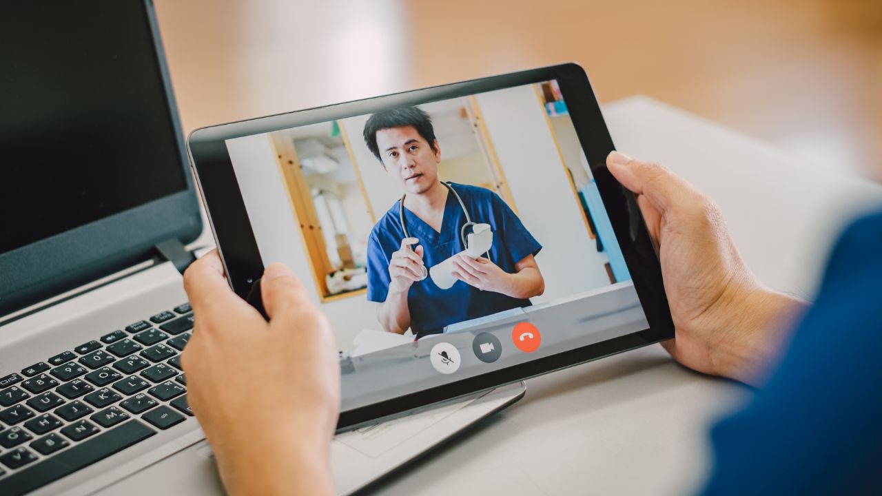Person holding a tablet during a telehealth video visit with a healthcare provider