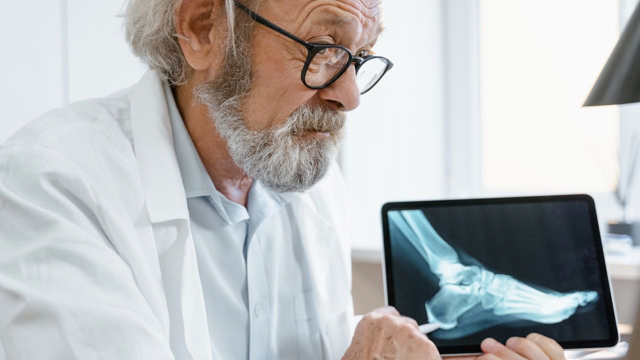 Senior doctor holding a tablet displaying an ankle X-ray during a telehealth consultation