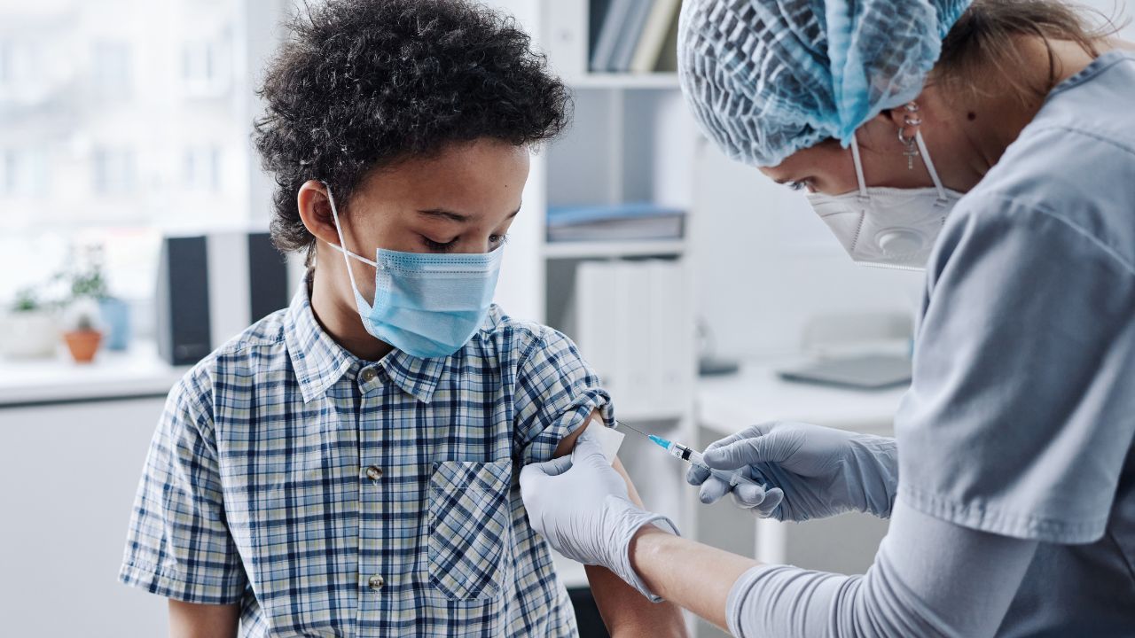 A nurse holding a thermometer and a patient in the background