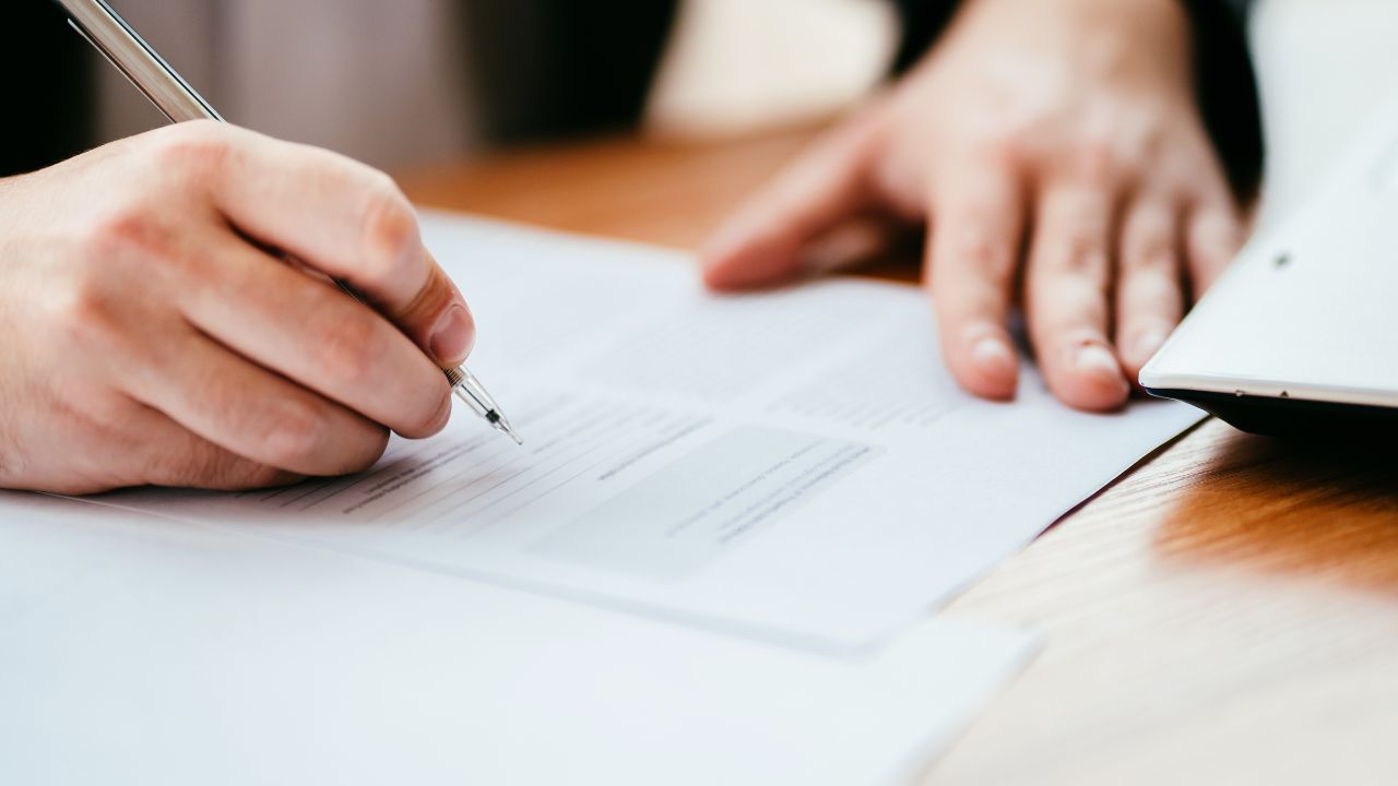a pair of hands at a desk signing a contract