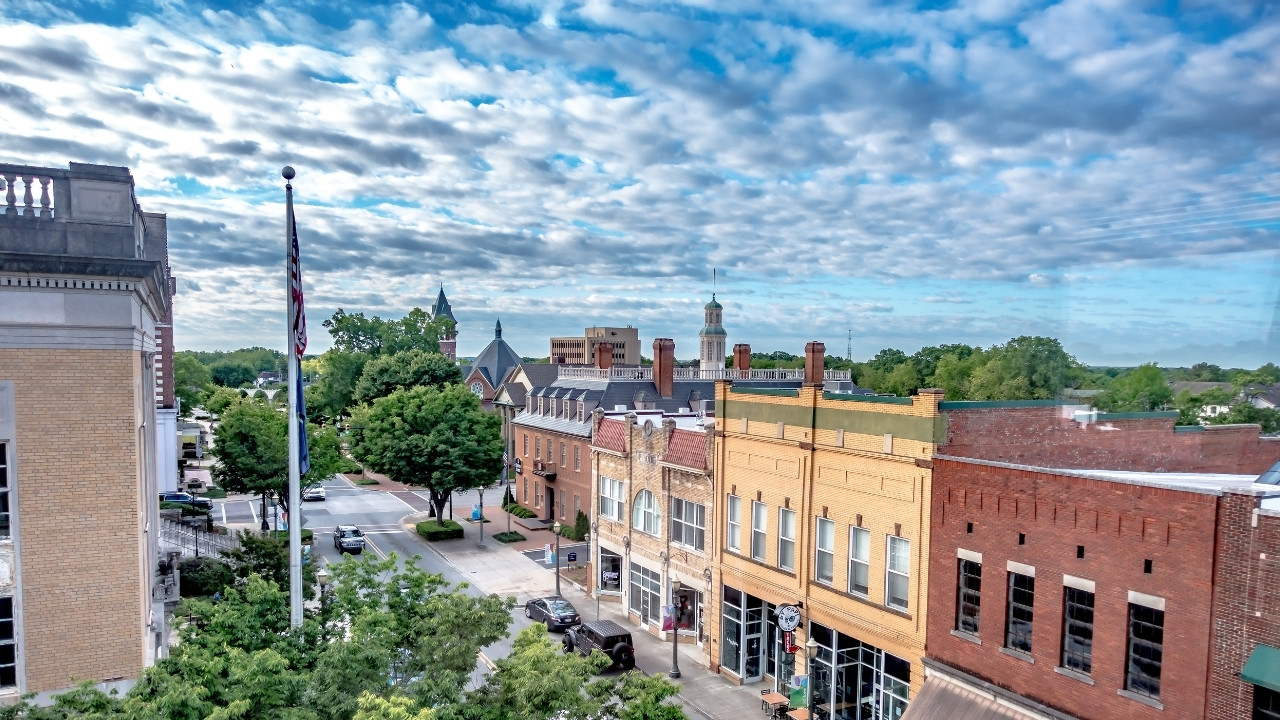 Aerial view of a small downtown street with trees and historic brick buildings