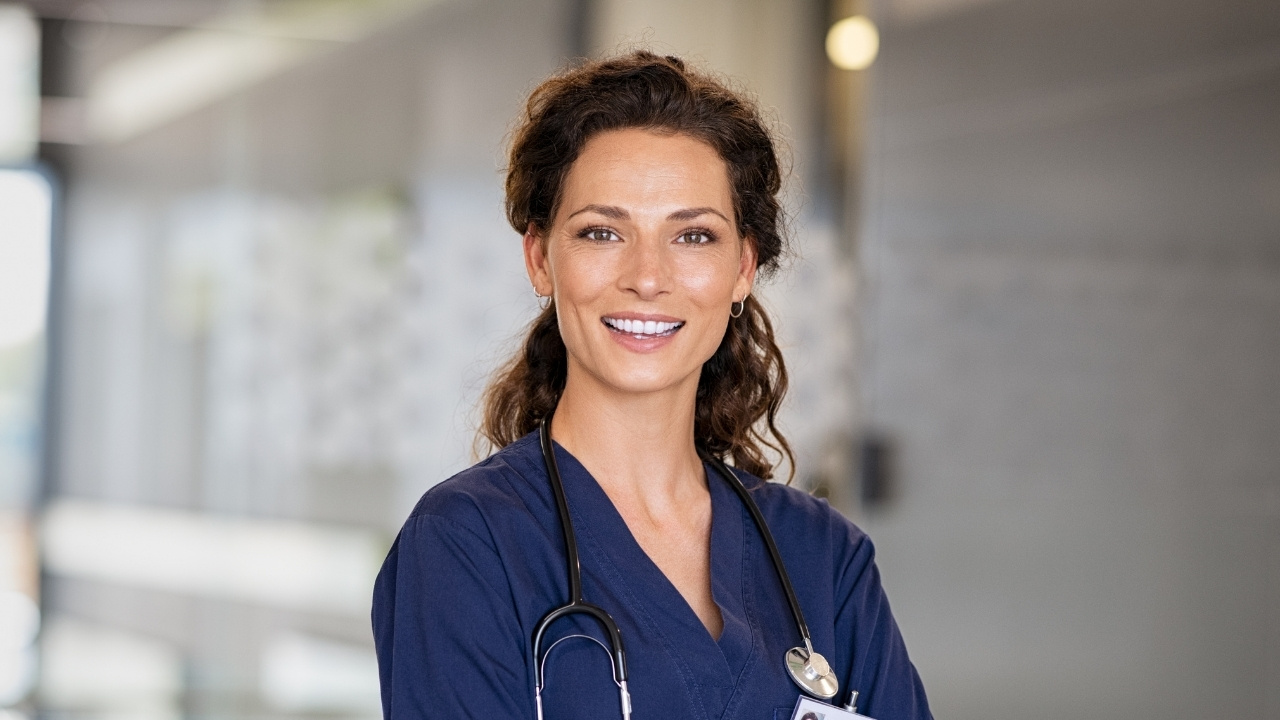 A photo of a smiling nurse holding a cup of coffee