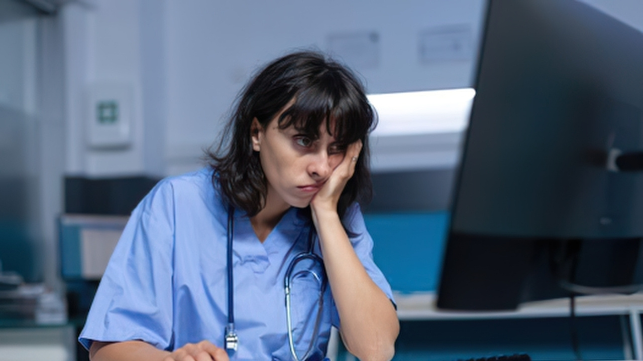 nurse looking worried and tired using a computer