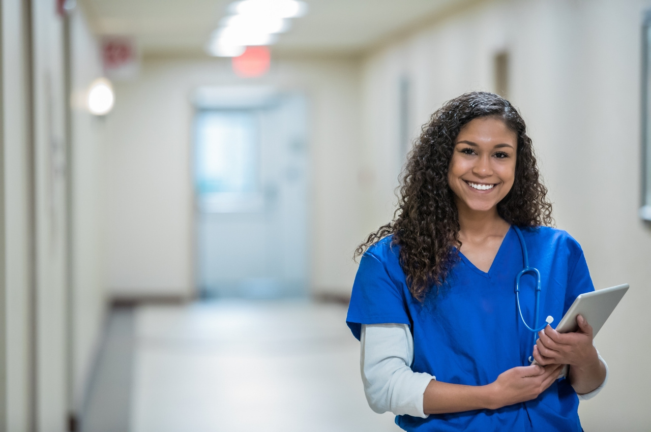 Nurse working and smiling in a hospital hallway