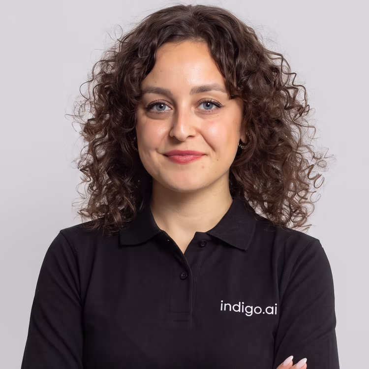 Membro del team di indigo.ai con capelli ricci e polo nera aziendale