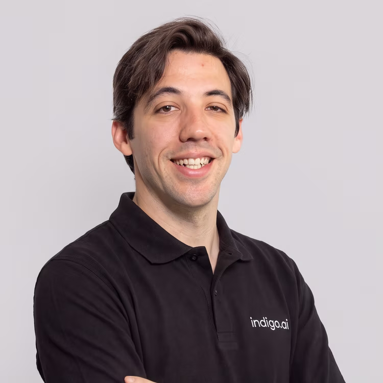 Membro del team di indigo.ai sorridente con la polo nera aziendale