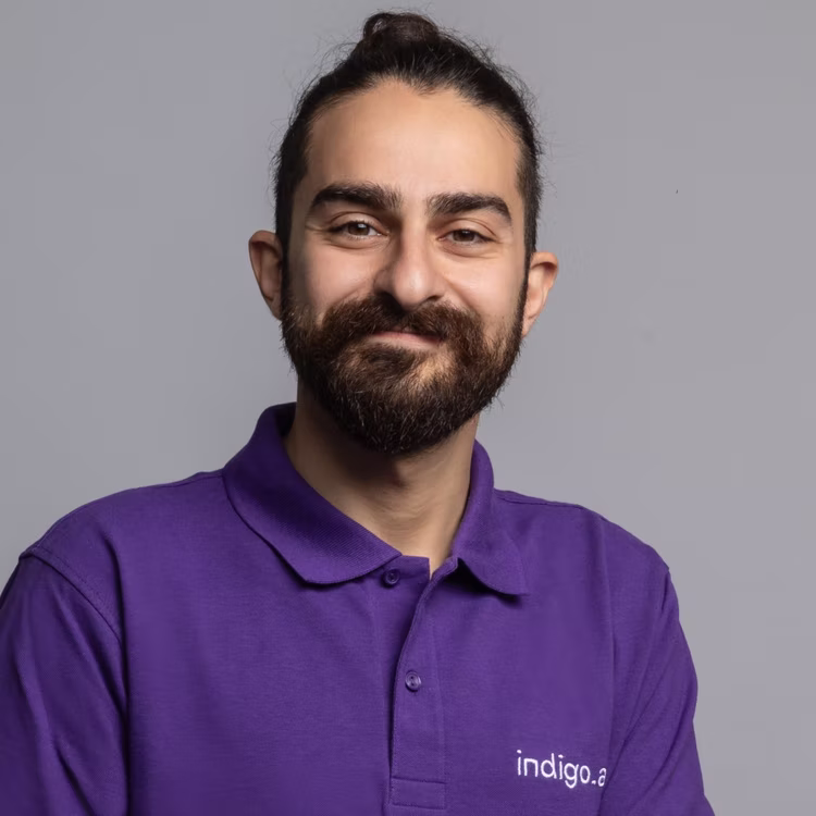 Membro del team di indigo.ai con barba e polo viola aziendale