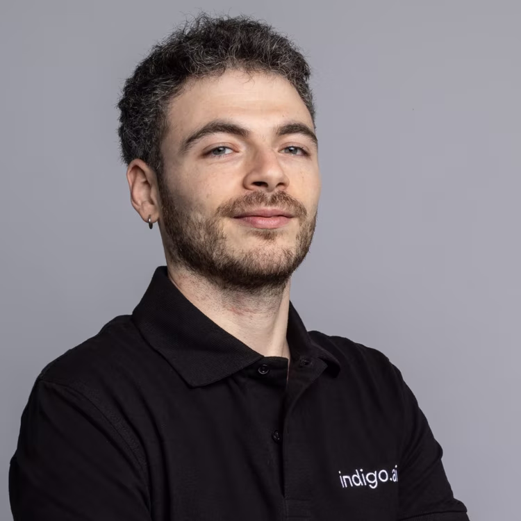 Membro del team di indigo.ai con orecchino e polo nera aziendale