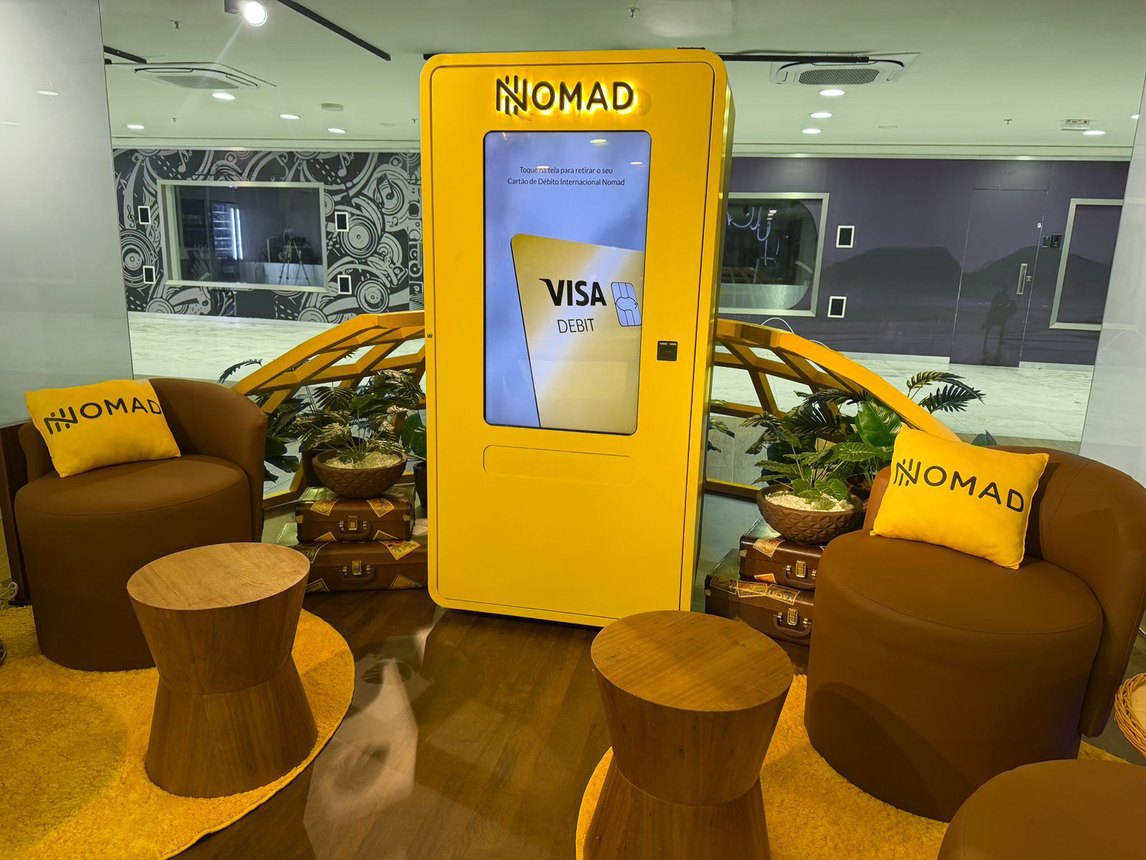 Totem Nomad para emissão do Cartão de Débito Internacional, entre poltronas com almofadas Nomad no Bossa Nova Mall